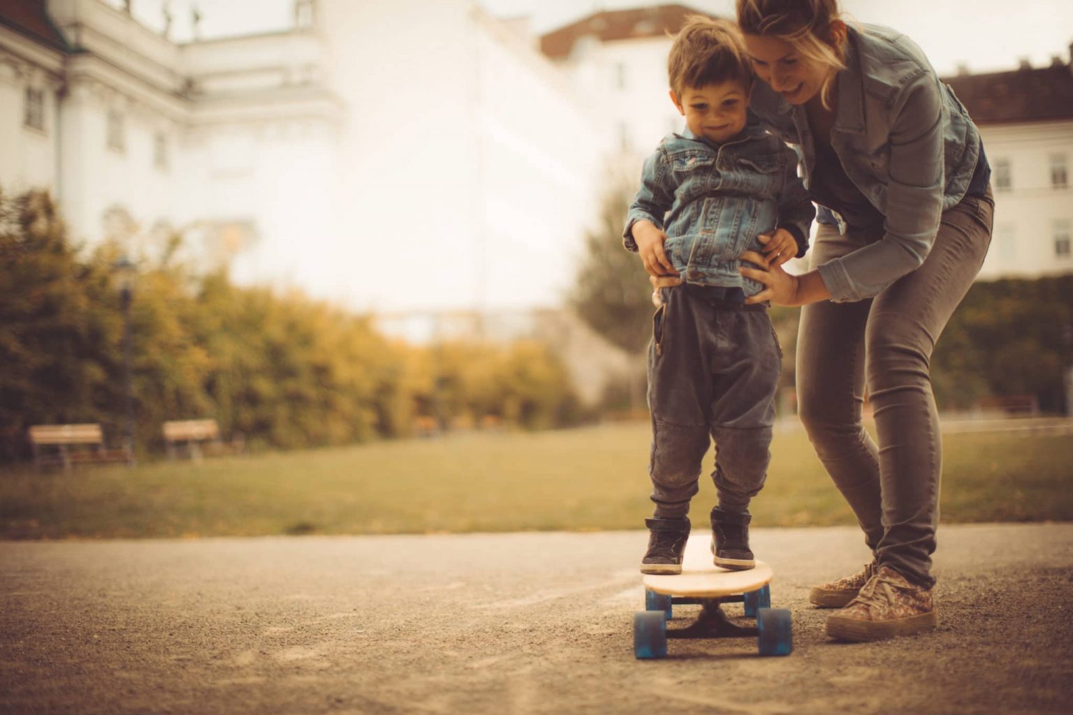 Children Pediatric Balance Disorder Child on Skateboard Being Held By Mother Due to Recently Diagnosed Balance Disorder
