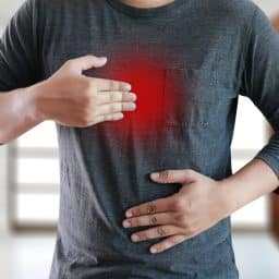 a man holds his stomach and chest in discomfort