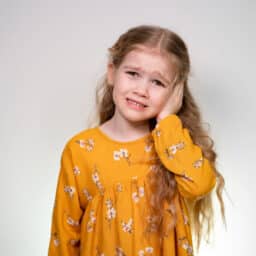 Young girl with earache holding her ear
