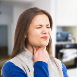 Woman with sore throat looking uncomfortable.