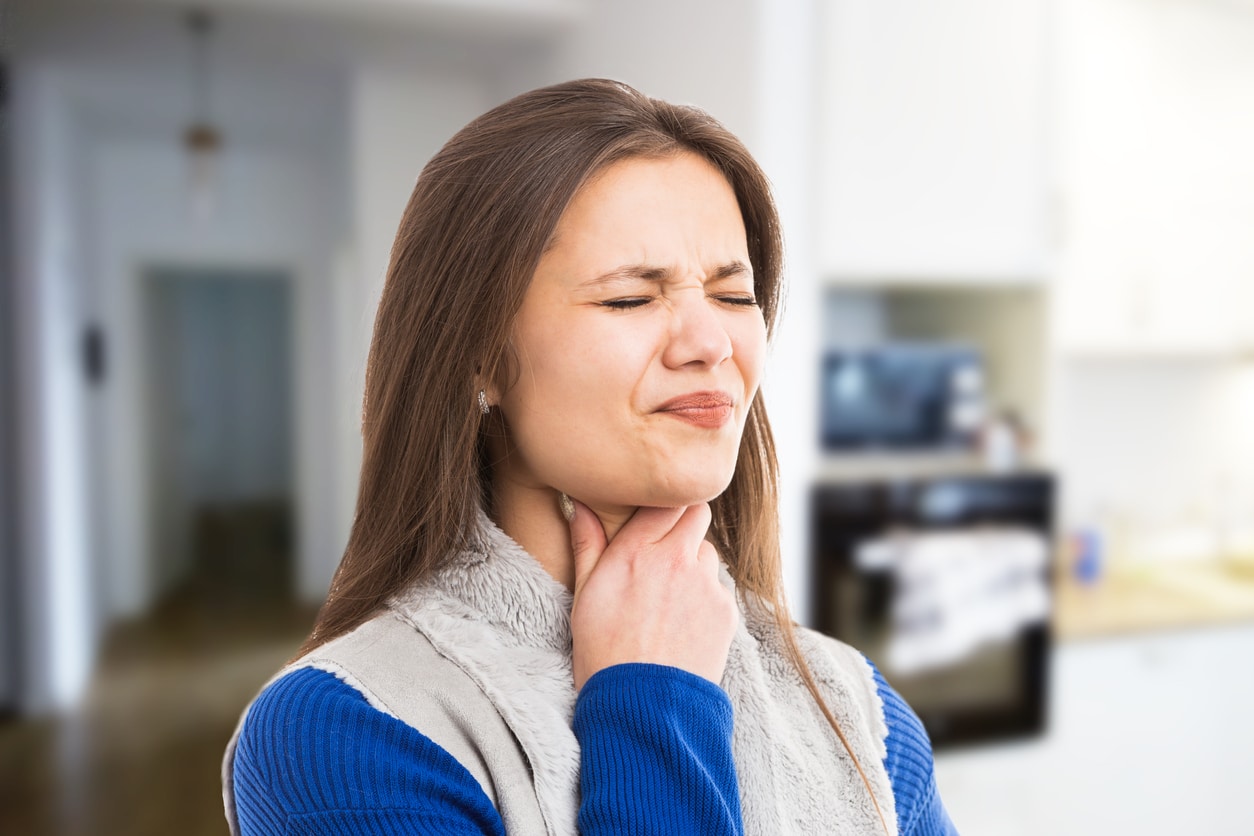 Woman with sore throat looking uncomfortable.