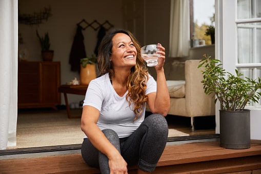 Relaxed, happy woman at home drinking water.
