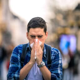 Middle Aged Man in Street Blowing Nose into Tissue